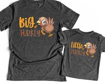 May include: Two dark gray t-shirts, one adult and one child size, with matching Thanksgiving-themed graphics. The adult shirt says "Big Turkey" and the child's shirt says "Little Turkey", both with cartoon turkey illustrations.