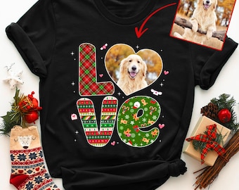 May include: Black t-shirt featuring the word "LOVE" in a festive design. The "L" is plaid, the "VE" has Christmas patterns, and the "O" has a golden retriever in a heart. A small image of the dog is in the top right.