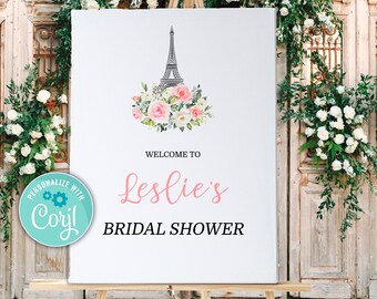 Könnte beinhalten: Ein weißes Schild mit einem rosa-weißen Blumendesign und einer schwarzen Silhouette des Eiffelturms. Das Schild lautet "Willkommen zum Bridal Shower von Leslie".