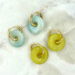May include: Four pairs of hoop earrings with a gold metal hoop and a round stone. Two pairs have a light blue stone and two pairs have a light green stone.