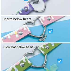 May include: A heart-shaped choker necklace with a silver metal charm in the center. The choker is made of purple leather with white and pastel-colored hearts. The charm is a bat with a glow-in-the-dark finish.