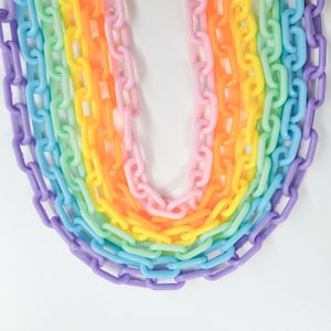 May include: A rainbow of plastic chains in various sizes, arranged in a U-shape. The chains are in shades of purple, blue, green, yellow, orange, and pink.