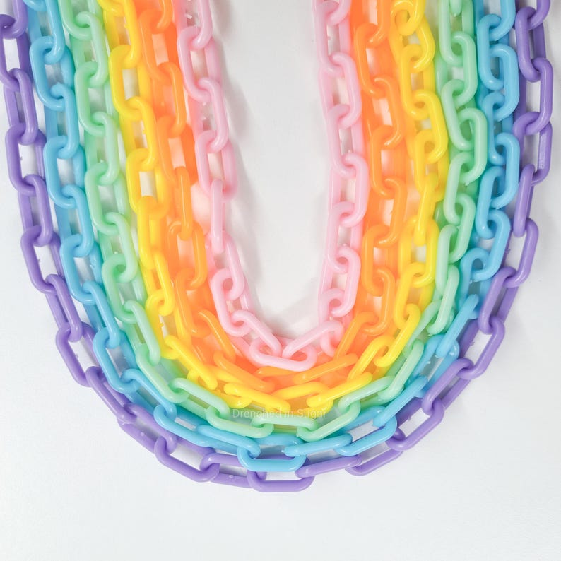 May include: A rainbow of plastic chains in various sizes, arranged in a U-shape. The chains are in shades of purple, blue, green, yellow, orange, and pink.