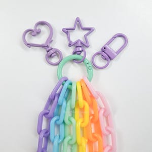May include: A rainbow colored plastic chain with a purple heart, star, and rectangle keychain charms attached to a green ring.