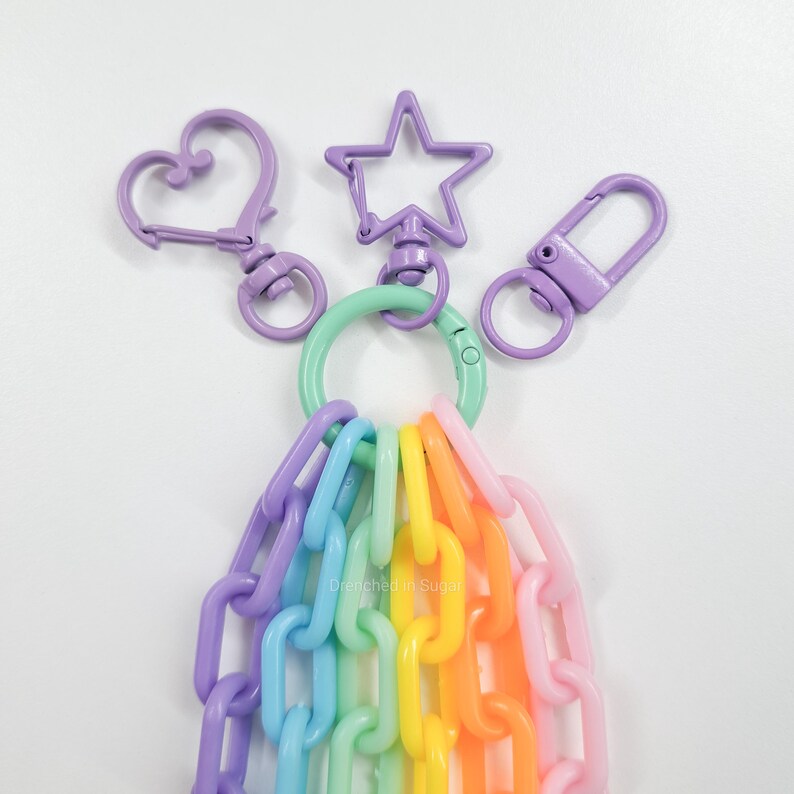 May include: A rainbow colored plastic chain with a purple heart, star, and rectangle keychain charms attached to a green ring.