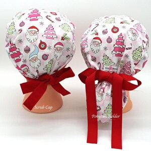 May include: Two scrub caps with a festive Christmas pattern featuring Santa Claus, Christmas trees, and ornaments on a white and pink checkered background. Each cap has a bright red bow. One cap is labeled "Scrub Cap" and the other "Ponytail Holder".