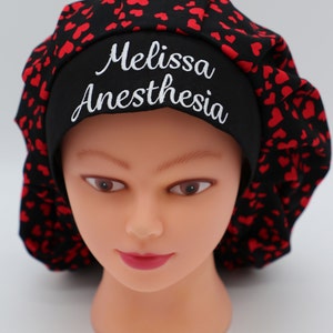 May include: Black scrub hat with a red heart pattern and the text "Melissa Anesthesia" embroidered in white.