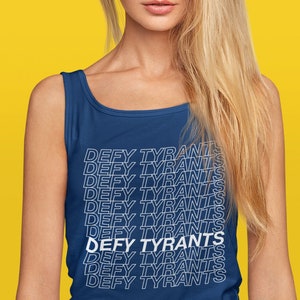 May include: A woman wearing a blue tank top with the phrase "DEFY TYRANTS" repeated in white text.