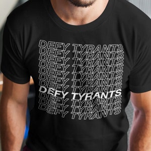 May include: A black t-shirt with the phrase "Defy Tyrants" repeated in white text.