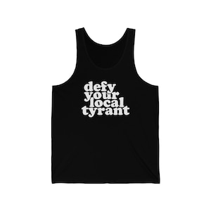 May include: Black tank top with the white text "defy your local tyrant". The sleeveless shirt has a scoop neck and is made of a soft material. The text is in a bold, retro font.
