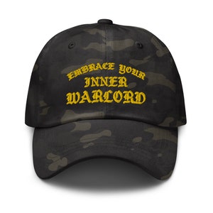 May include: A black and green camouflage baseball cap with the text "Embrace Your Inner Warlord" embroidered in yellow.