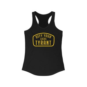 May include: Black racerback tank top with the text "DEFY YOUR LOCAL TYRANT" in a yellow, retro-style design. The text is inside a yellow, rounded rectangle. The tank top has a scoop neck and a racerback design.