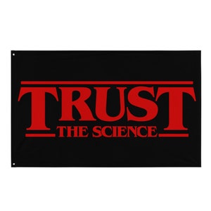 Puede incluir: Bandera negra con las palabras "TRUST THE SCIENCE" en letras rojas.