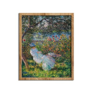 May include: A framed oil painting print depicting a figure in a light blue dress sitting under a tree in a garden. The scene features vibrant green foliage, colorful flowers, and a wooden fence in the background, all enclosed in a light brown frame.