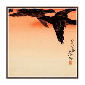 May include: A square framed print featuring two black crows in flight against a gradient background that transitions from a deep orange at the top to a pale cream at the bottom. Black Japanese calligraphy and a small red seal are visible on the right.