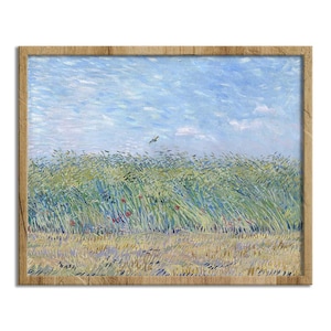 May include: A framed print of a landscape painting. The artwork depicts a field of tall, green and yellow grass under a blue sky with a few clouds. A bird flies in the distance. The frame is made of light brown wood.