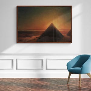 Puede incluir: Una impresión de arte mural rectangular en un marco marrón oscuro que presenta un paisaje de las pirámides egipcias al atardecer. La escena muestra siluetas de grandes estructuras triangulares contra un cielo naranja oscuro y profundo.
