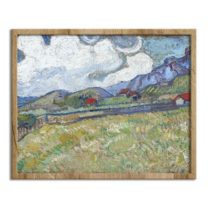 May include: A framed landscape painting with a wooden frame. The artwork depicts a vibrant countryside scene with rolling hills, houses, and a cloudy sky. The color palette includes greens, blues, and reds, creating a textured, impressionistic style.