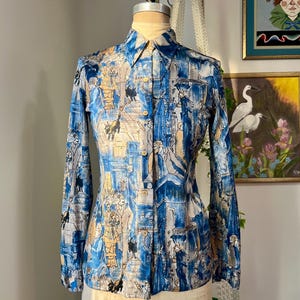 Peut inclure: Une chemise à manches longues boutonnée bleu et beige avec un imprimé fantaisiste de personnes et d'animaux. La chemise a une silhouette ajustée et un col pointu.