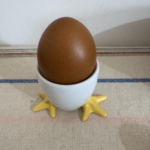 Ein Retro-Sammlerspaß, schrullig weißer Porzellan-Eierbecher mit gelben Klauenfüßen