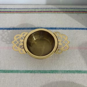 An exquisite  two part gold coloured metal tea strainer  with drip stand