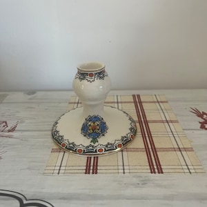 A vintage white bone china candle holder  with an interesting black, red and blue design