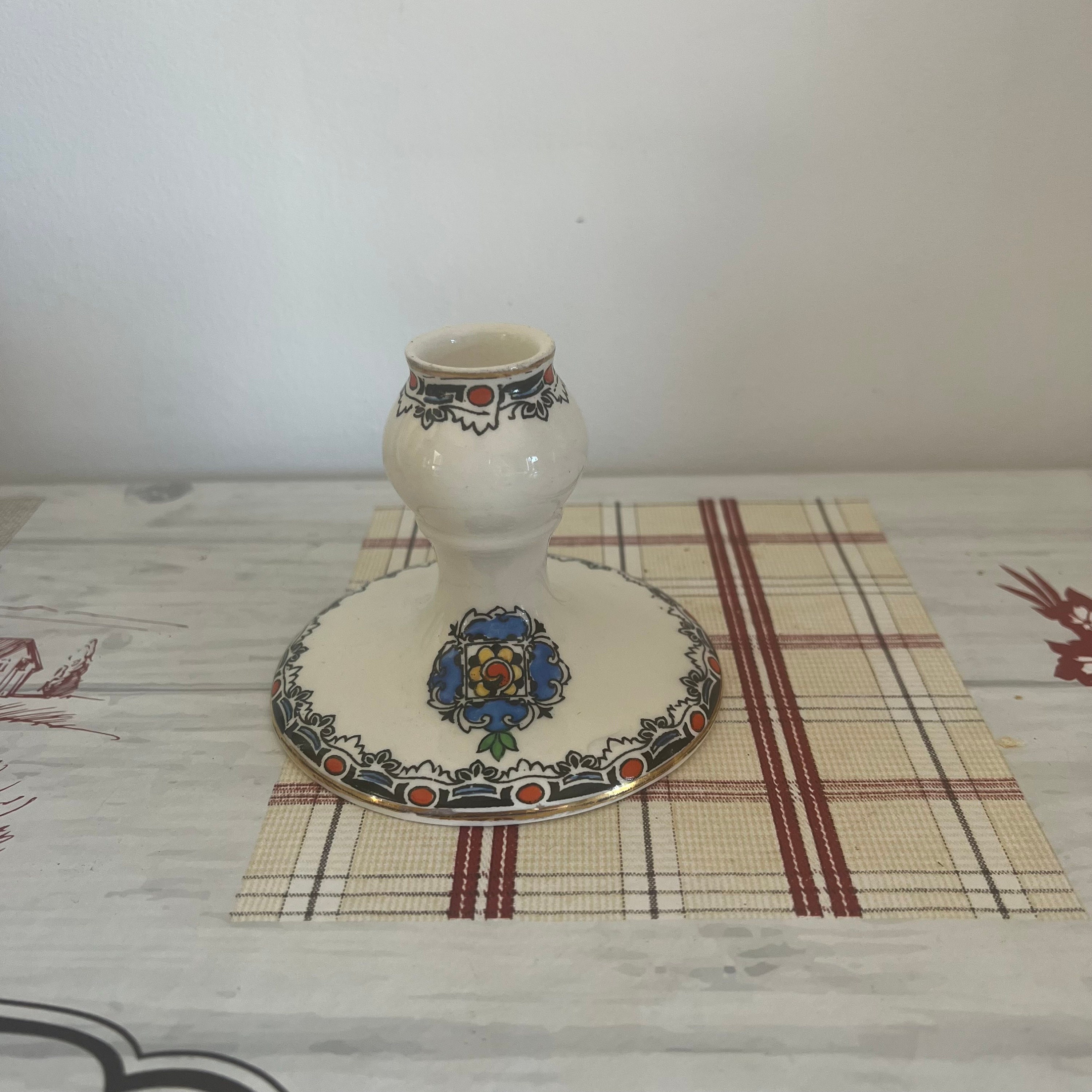 A vintage white bone china candle holder  with an interesting black, red and blue design