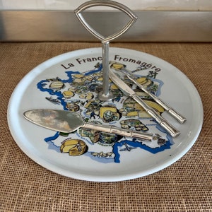 Une assiette à fromages vintage en porcelaine de La France Fromagere avec des emporte-pièces, une fourchette et une poignée de transport en métal argenté Avon