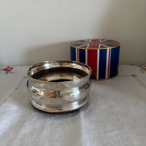 An antique  decorative  silver plated, felt backed wine or champagne table coaster