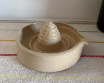 Een origineel, uniek, met de hand gemaakt beige geglazuurd aardewerksap, citroenpers