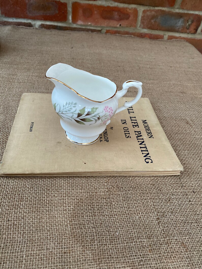 A Paragon fine bone china jug with a green and pink pattern and a gold rim around the top and base