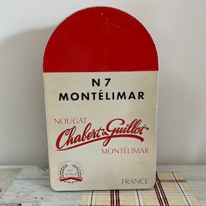 A large red and white N7 Chabert & Guillot  Montelimar nougat tin with distances to major world cities on each side