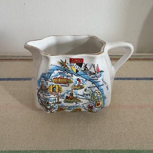 Jarra de porcelana blanca retro para leche con un mapa detallado de Norfolk en un lado y borde dorado