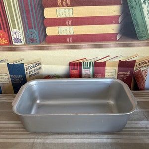 May include: A silver rectangular baking pan with slightly rounded edges. The pan is sitting on a striped tablecloth.