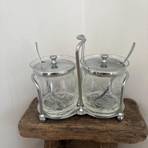 Un support vintage en cristal gravé et acier inoxydable poli pour pots à confiture et à marmelade, avec couvercles et cuillères (7 pièces au total).