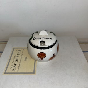 May include: White ceramic chutney jar with a lid. The jar has a black rim and brown onion illustrations. The lid has a black rim and the word "CHUTNEY" written in black.