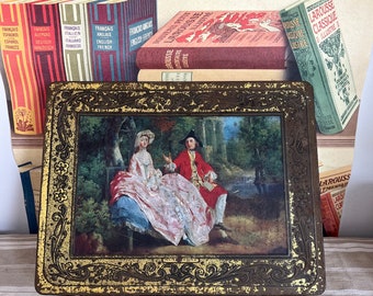 A very large antique gold coloured  tin with a hinged lid  Made in Belgium - with a painting of a courting aristocratic couple