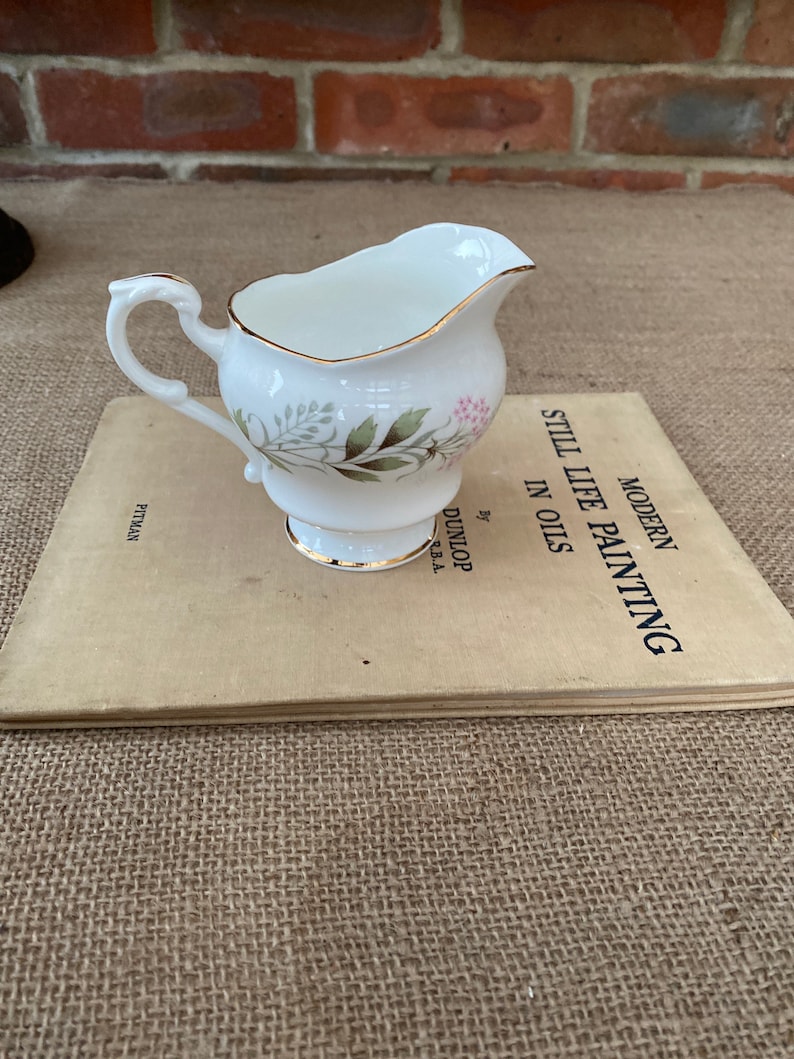 A Paragon fine bone china jug with a green and pink pattern and a gold rim around the top and base