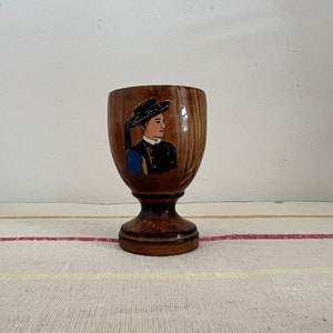 A  French vintage solid wooden footed egg cup with a picture of a man painted on the side