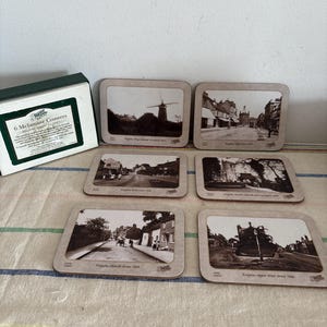 May include: A set of six melamine coasters featuring vintage black and white images of buildings and streets. The coasters are in a box with the text "6 Melamine Coasters". Each coaster has a different image and text.