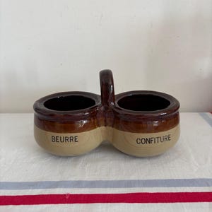 A vintage French farmhouse duo set of glazed rustic stoneware beurre et confiture, butter and jam pots joined by a central handle