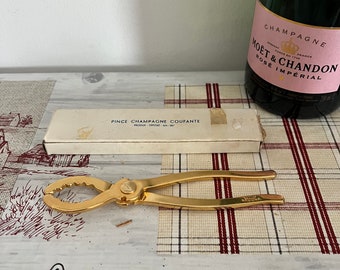 Un metal vintage de color dorado 'Pince Champagne Coupante', herramienta de apertura de champán, removedor de corcho