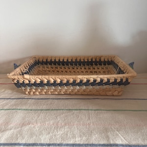 May include: A woven rectangular tray with blue and white accents. The tray is made of natural materials and has a rustic look.