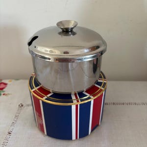 En retro vintage gryta i rostfritt stål med lock och utskuren sked