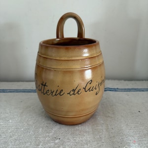 En fransk vintage beige stengodsgryta 'Batterie de Cuisine' för att ha träskedar och spatlar nära till hands vid spisen.