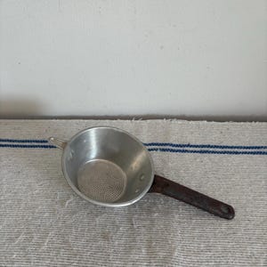 A well used French vintage  finely perforated aluminium sieve with steel handle