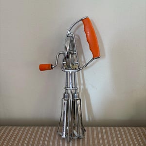 An original vintage  French retro 1960s  stainless steel egg beater hand whisk with orange plastic   handles