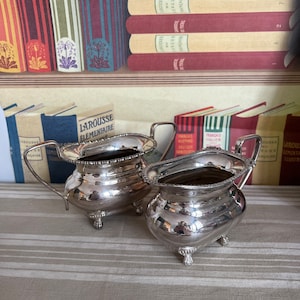 A  decorative vintage Viners Alpha Plate duo of silver plated creamer and sugar bowl on raised feet