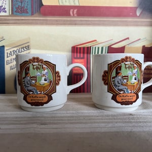 A pair of vintage Villeroy and Boch, Luxemburg coffee or tea mugs &#39; De Koffie wordt geserveerd&#39;