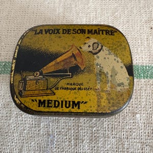 Um telefone de gramática francesa vintage original da década de 1930, caixa de metal com agulha média, tampa de lata (com algumas agulhas)